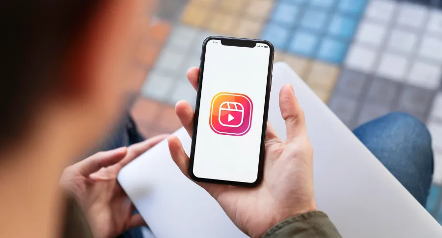 A man holding a phone with Instagram reel's logo on it