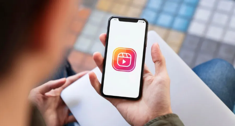 a man looking at his phone with the Instagram reel logo on it