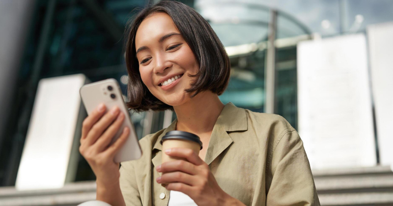 happy girl checking phone and drinking coffee