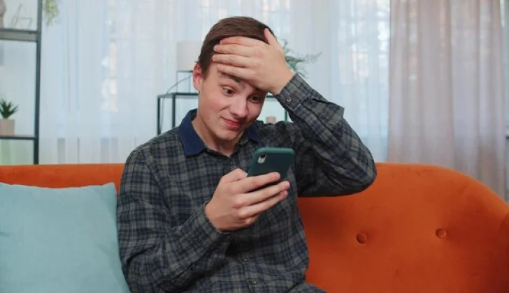 guy checking his phone looking tired