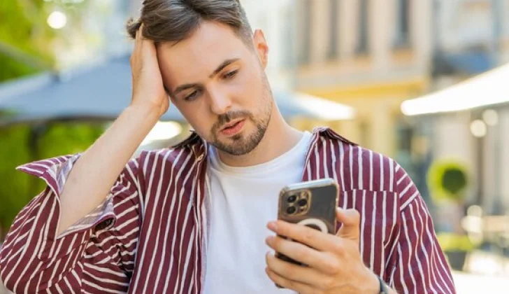 a guy checking his phone looking frustrated