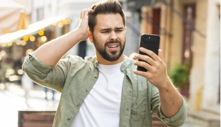 a person checking his phone looking confused