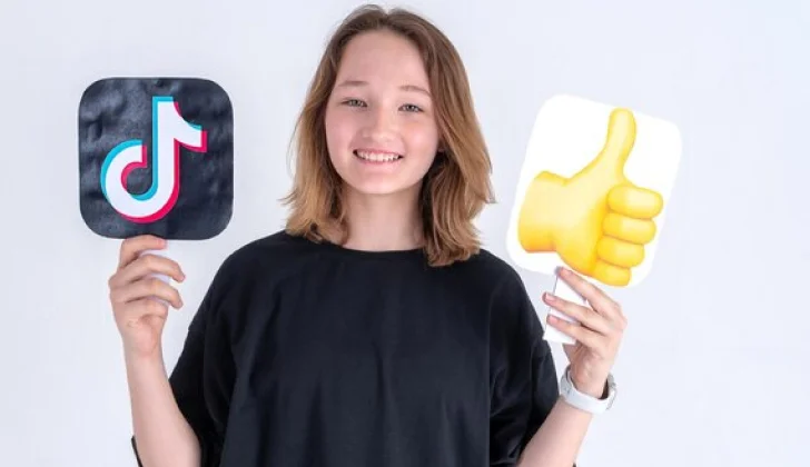 a girl holding a TikTok sign