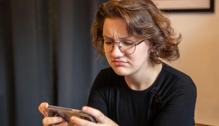 a girl checking her phone frustrated