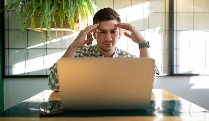 a frustrated person behind the laptop
