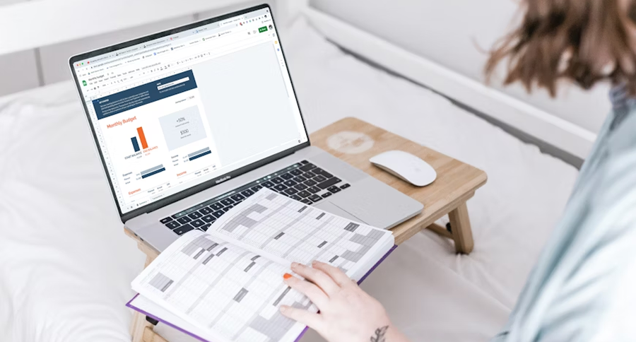 A woman sitting on bed, working on a laptop