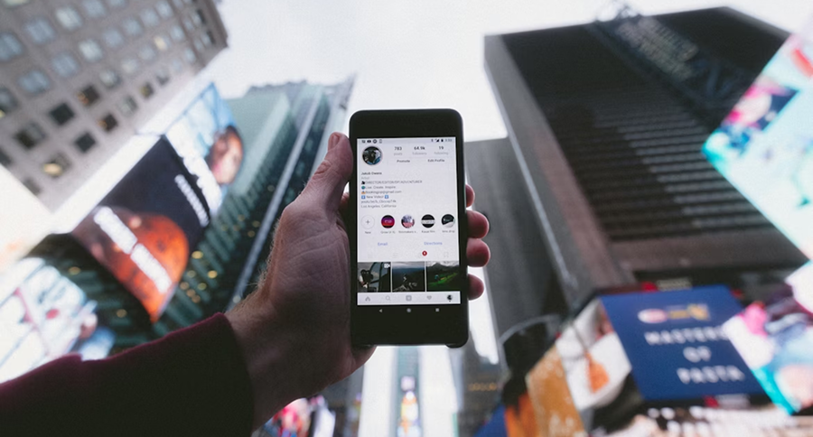 A phone showing Instagram profile with a background of downtown