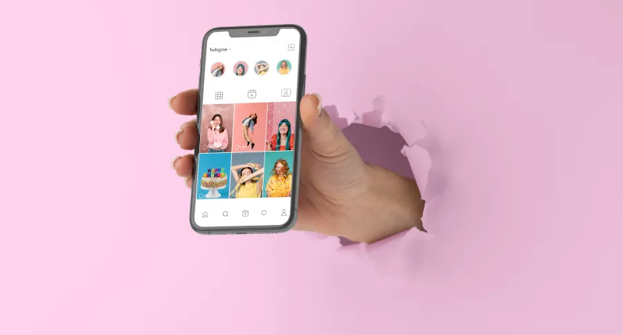 a hand coming out of paper holding a phone showing an Instagram page