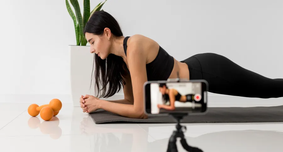a fitness influencer filming a video (a black haired woman in work out clothes)