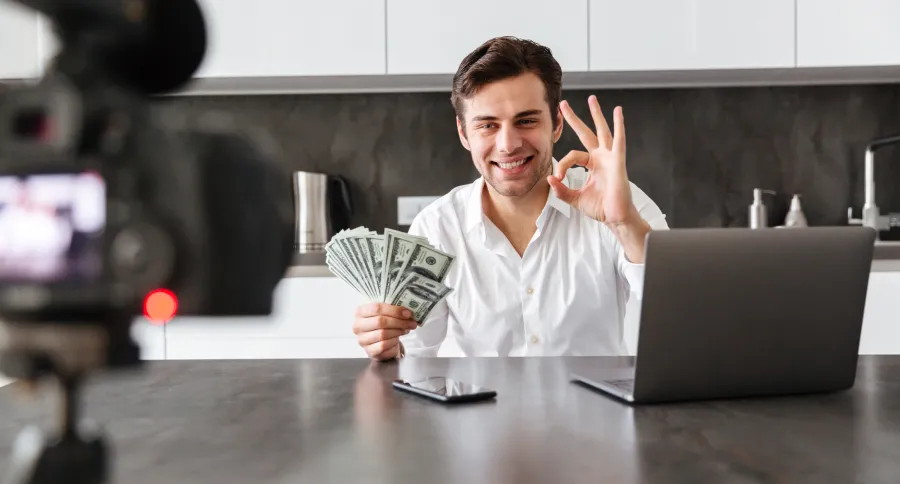 A man filming win front of a camera with a bunch of money in hand