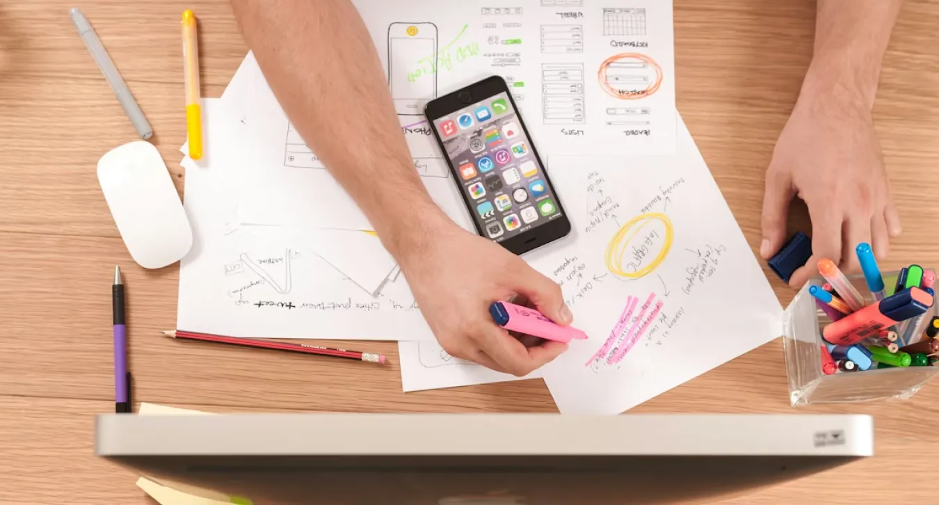 a man working on a desk with his phone and laptop and notes describing different contents