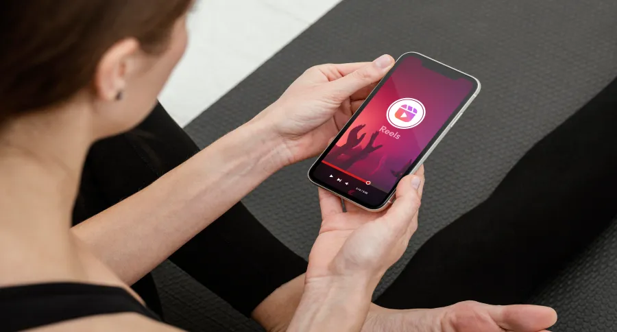 a woman watching Instagram Reels while sitting on a yoga mat