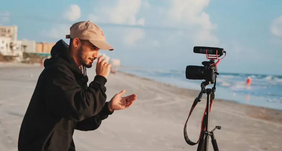 a man filming himself on a beach with a camera on a tripod