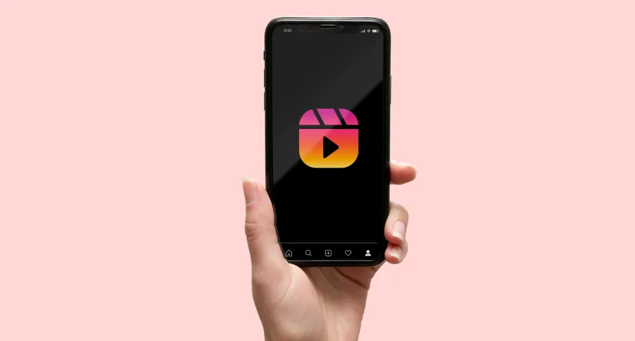A hand holding a phone showing Instagram Reel logo