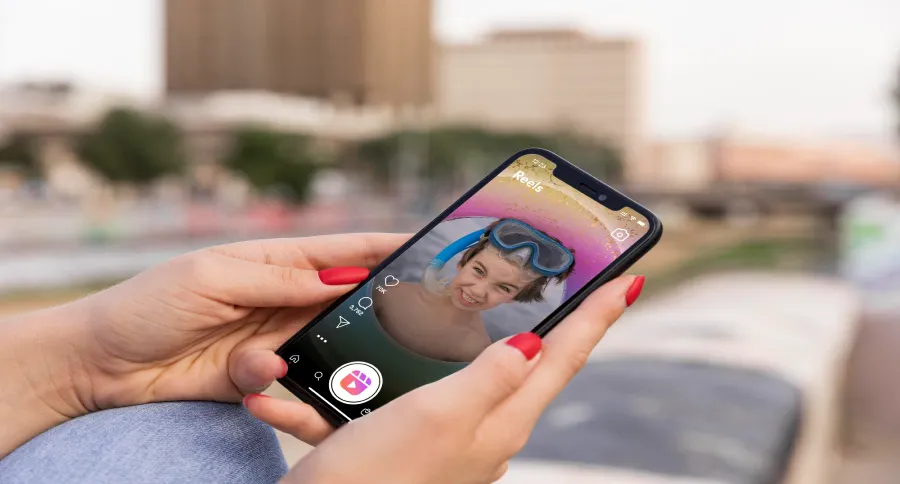 A woman holding a phone watching Reels on it