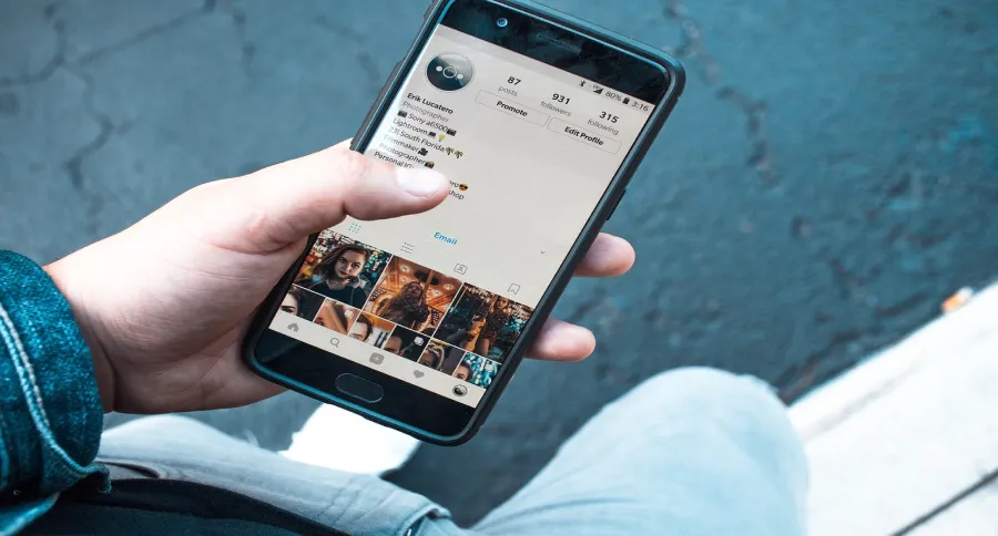 A man holding a phone showing an Instagram account's profile page